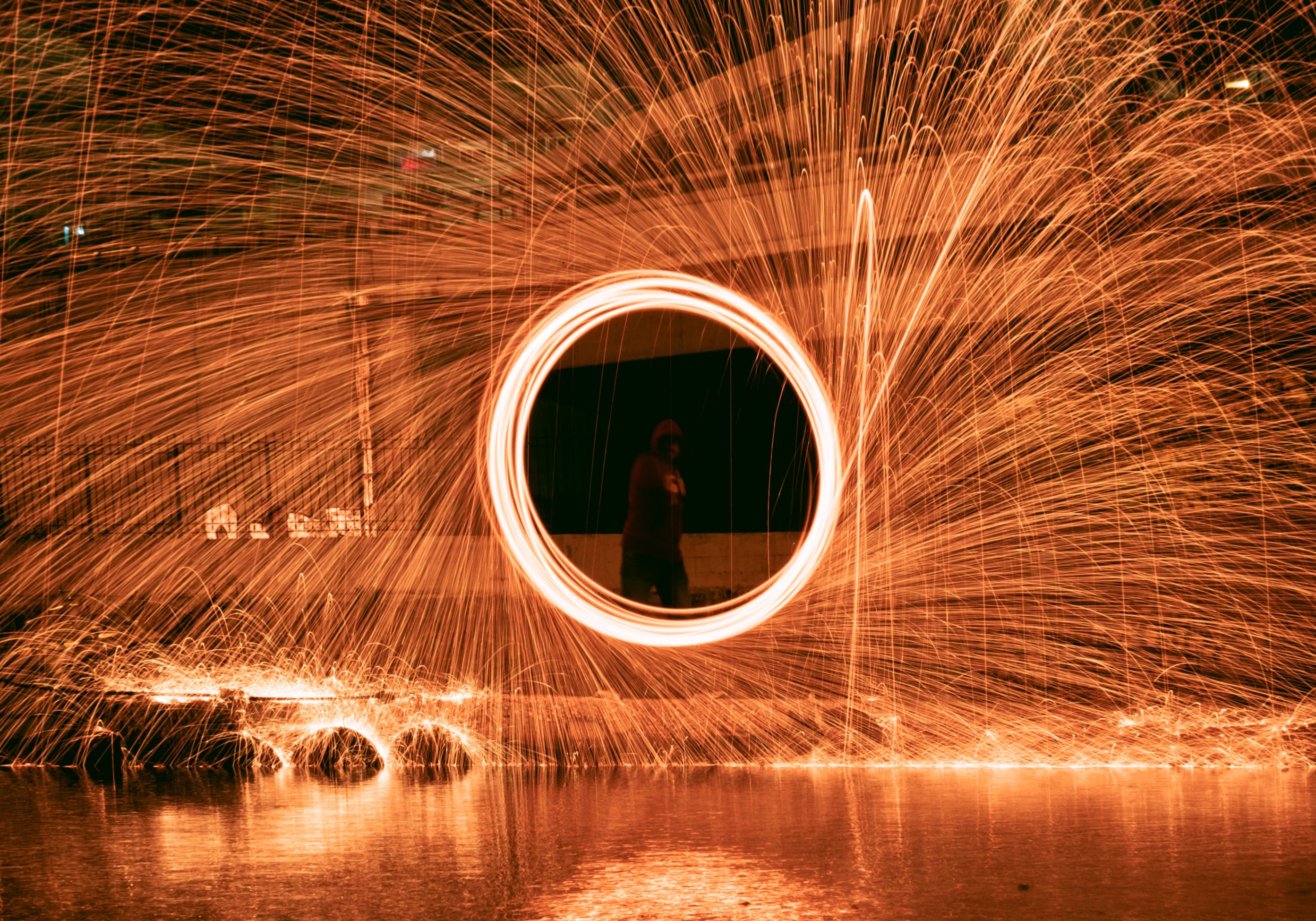 A man in the middle of a circle created by the afterimage glow of sparklers